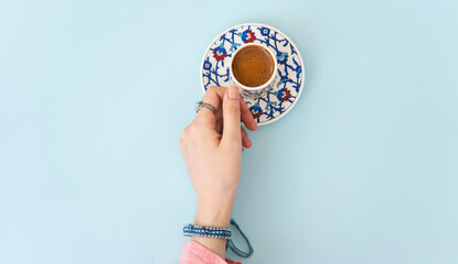 Woman hand holding traditional porcelain turkish coffee cup