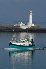 Fishing boat with a moor lighthouse in the background.