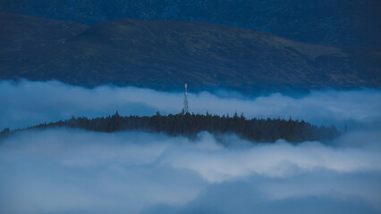 Lonely radio tower in the mountains above the clouds.