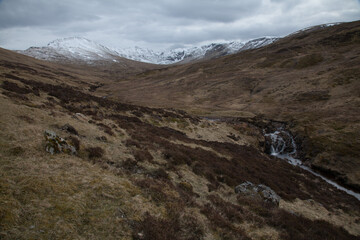 View of the Scottish moors and snowy peaks with a small waterfall