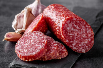 Traditional smoked salami sausage with spices.Salami sausage slices on a black chopping Board. Dark...