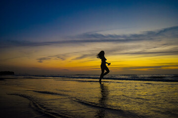 person running on the beach at sunset