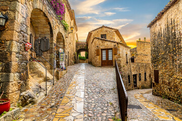 The medieval Spanish village of Pals in the Costa Brava region of Southern Spain as the sun sets after a summer rainstorm. - obrazy, fototapety, plakaty