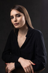 Portrait of a young brunette with long hair in the studio. Dramatic photo in dark colors.