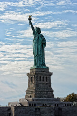 Obraz na płótnie Canvas NEW YORK, NY - 04 NOV 2019: Statue of Liberty and pedestal with tourists around the base on a blue cloudy sky day.