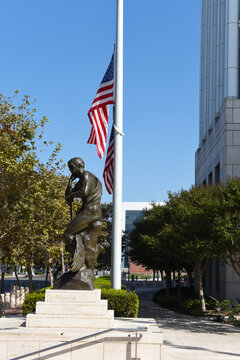 SANTA ANA, CALIFORNIA - 23 SEPT 2020: Statue with flag at Half Mast at the Ronald Reagan Courthouse and Federal Building.