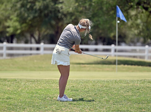 Young girl chipping the golf ball on the green during a golf tournament