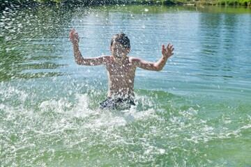 Happy boy splashing in a lake in Norway