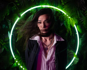 Naklejka premium Portrait of an Asian man against the background of a circular lamp in the studio with neon light. 