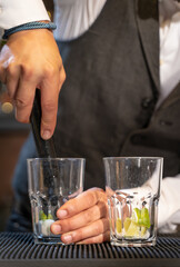 Elegant barman making cocktail Mojito in night club adding ingredients and creating expert drinks on bar counter.