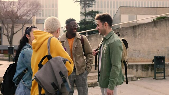 Group of multiracial university student friends laughing together and talking on college campus after class. Slow motion high quality 4k footage