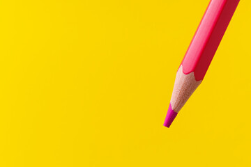 Colored pencil close-up with selective focus on the stylus and a blurred yellow background. Copy...