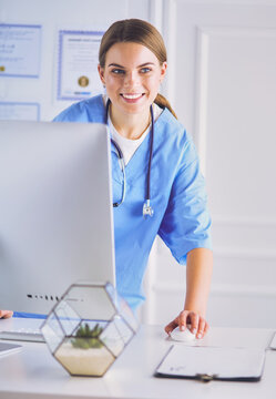 Young doctor woman standing near table, isolated on white background