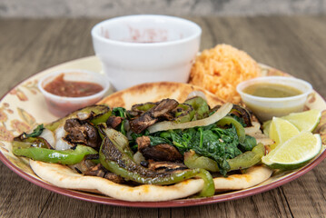 Thick homemade tortilla holds two vegan tacos loaded with stir fry vegetables, cilantro and salsa dipping sauce for a fullfilling meal