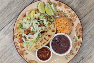 Overhead view of thick homemade tortilla holds a shrimp taco loaded with seafood, cilantro and salsa dipping sauce for a fullfilling meal