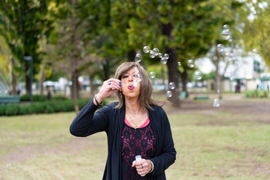 Mature Trans Woman Blowing Bubbles In A Park