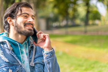Young latin man talking on cell phone in a park