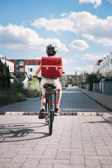 Back to school by bicycle, girl with brown helmet and red rucksack, sustainable transport