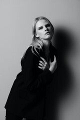 Obraz premium Blonde in a suit hugs herself while putting on a jacket