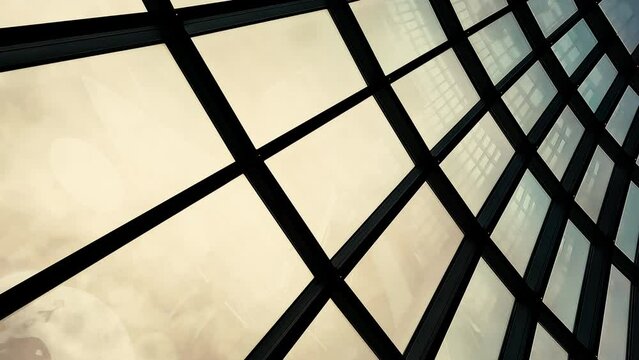 Futuristic looking large dome metal skylight arches above the frame. The moody overcast sky can be seen through the window, as well as interior reflections.