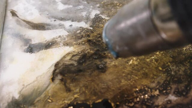 Electric dryer is blowing and spreading the fluid acrylic paints mixed with epoxide on the canvas. fluid art therapy.