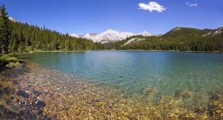Sawback Lake Green Emerald Water in Front Ranges of Banff National Park with Distant Canadian Rocky Mountain Peak on Horizon