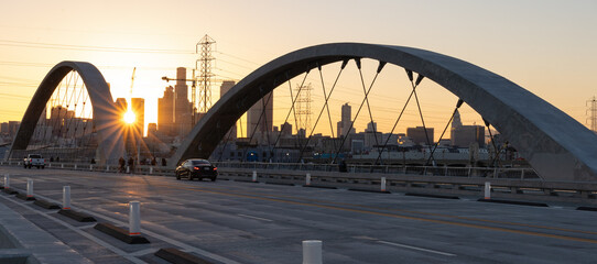 Lens flare at sunset on the 6th street bridge in Los Angeles with the skyline in the distance - obrazy, fototapety, plakaty