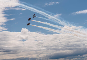 Three planes fly against a blue sky with white clouds