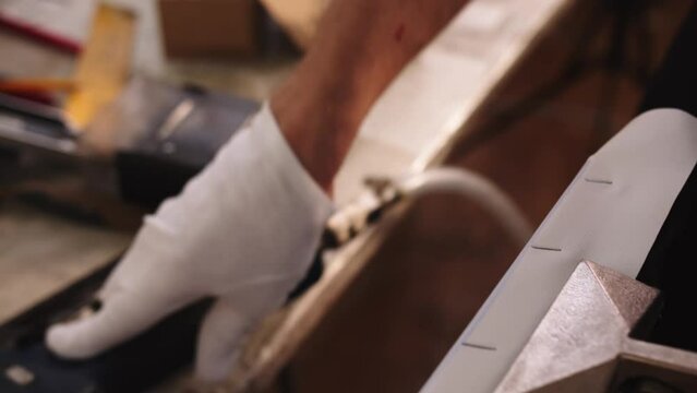 Close-up of making canvas for a painting in the art workshop. the hands in protective gloves are stretching the canvas over the picture frame with special tools.