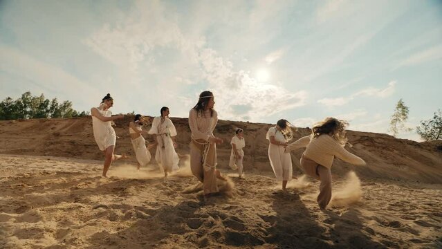 4k video group of dancing on sand. Sunset, shadow, slow-mo consept. Rural, ethic and national dance in summer desert.