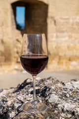 Glass of red dry wine and ruins of medieval castle of Châteauneuf-du-Pape ancient wine making village in France