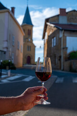 Tasting of red wine by old wine maker in Pierres Dorées region with yellow stone houses on south of Beaujolais region, France