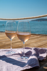 Glasses of cold rose wine from Provence served outdoor on wooden yacht pier with view on blue water and white sandy beach Plage de Pampelonne near Saint-Tropez, France