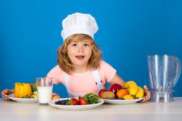 Child chef dressed cook baker apron and chef hat isolated on studio background. Healthy nutrition kids food.