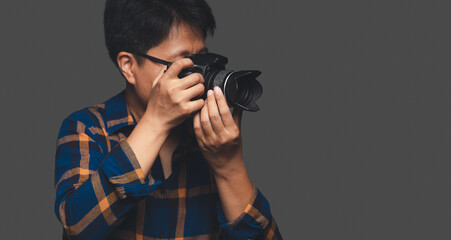 A Photographer holding a digital camera while standing on a gray background