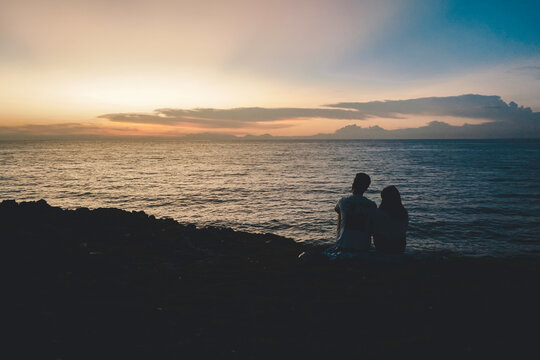 Shilloutte of a romantic couple dating in a beach during a sunset
