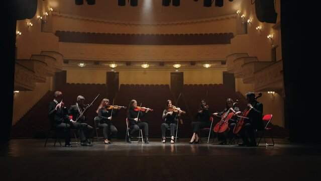 orchestra on scene of opera house, four violins, two cellos, bassoon and flute, musicians playing