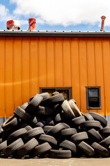 Stacked tires await disposal outside of a tire repair shop.