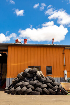 Stacked tires await disposal outside of a tire repair shop.