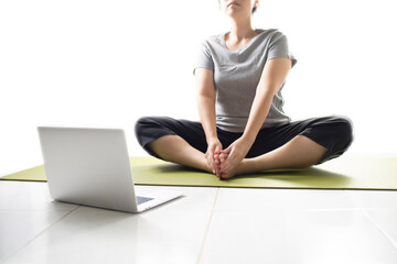 Women using laptop learning yoga at home via yoga online training. Woman studying yoga at home via videoconferencing. women start to practice meditation.