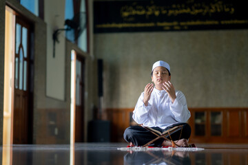 A little Asian Muslim boy is praying with peace in the mosque, giving a powerful atmosphere of faith, with copy space.