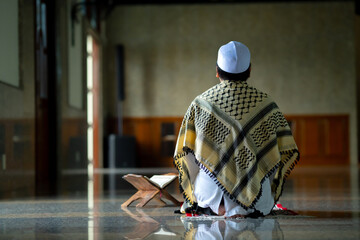 A little Asian Muslim boy is praying with peace in the mosque, giving a powerful atmosphere of faith, with copy space.