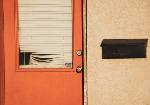 Orange urban door on rundown building with broken blinds