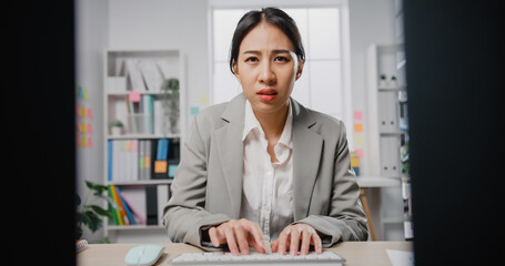 Young Asia businesswoman sitting on desk with laptop under stress from too much work in the office....