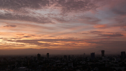 Fototapeta na wymiar panoramic photo of a beautiful sunrise in mexico city with volcanos in the background (Iztaccíhuatl, popocatepetl).