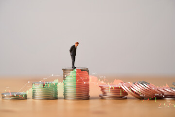 Miniature figure standing on highest coins stacking with increasing and decreasing stock market graph and chart for Business investment growth and Economic recession concept. - obrazy, fototapety, plakaty