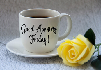Good morning Friday text on coffee cup yellow flower on blurred marble background.