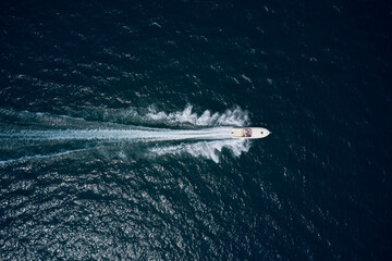 White speedboat on black water top view. White boat moving fast in the ocean aerial view.