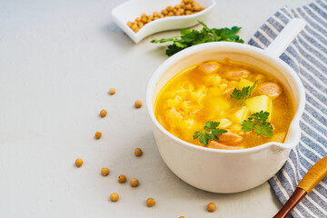 Traditional tasty pea soup with smoked sausage served in white bowl