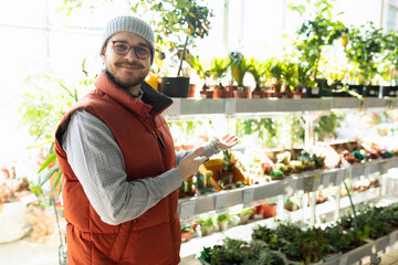 happy customer in hardware store next to shelves with potted plants